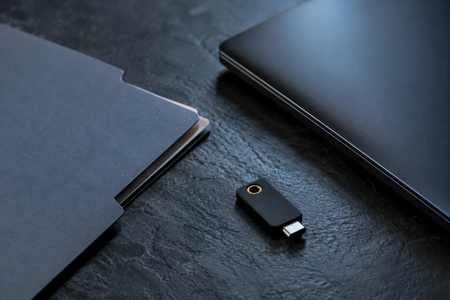 Illustrative close-up of a blank payroll folder, security key, and closed laptop